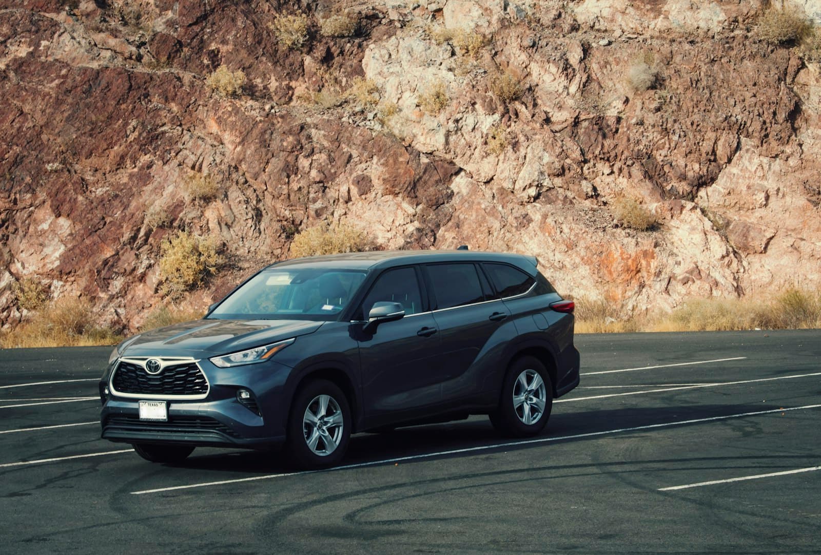 Grey family SUV parked in front of a rocky hillside